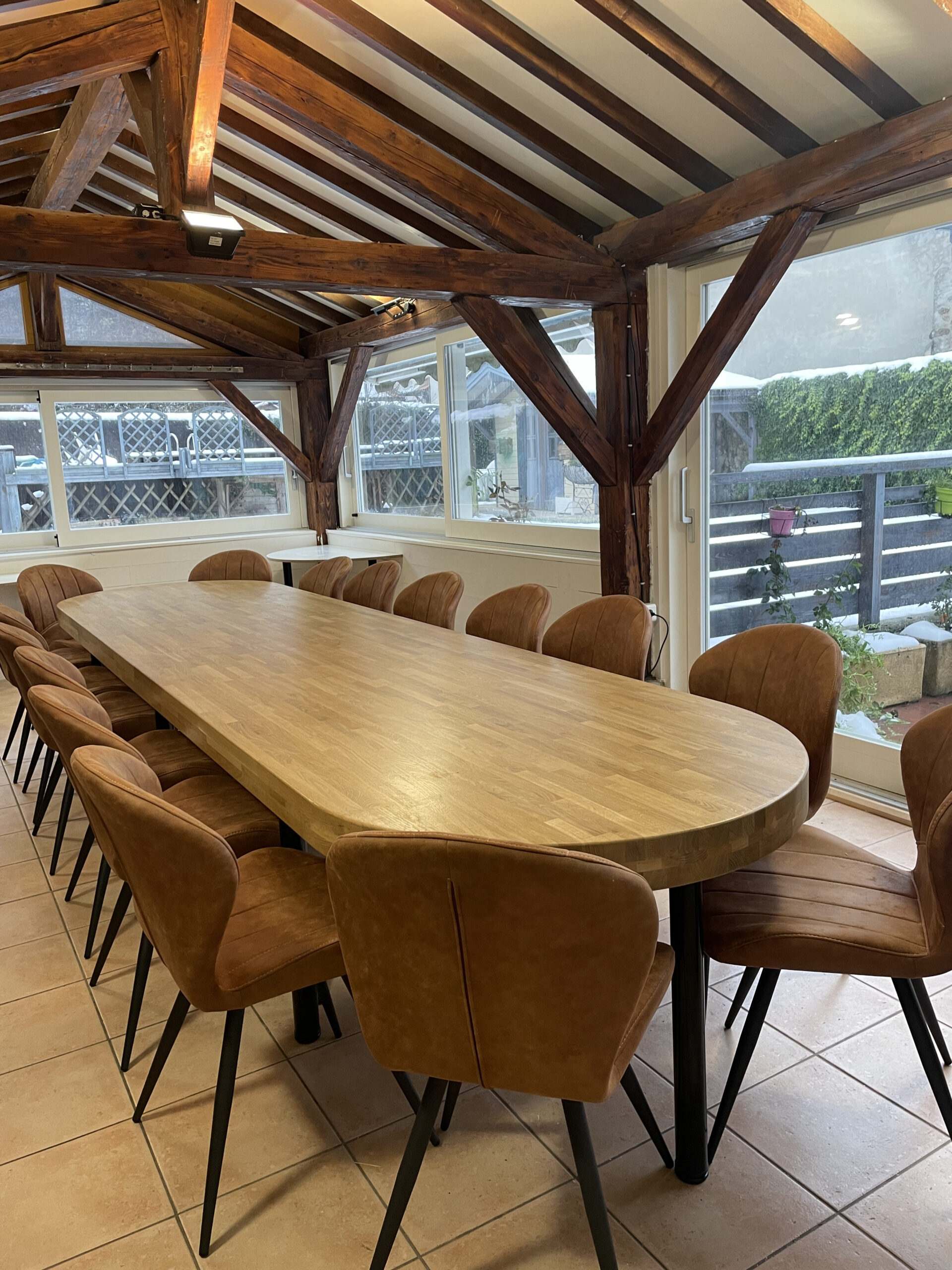 Véranda avec une longue table en bois et chaises